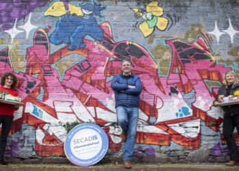 Trainers involved in the free sustainability programme by SECAD pose in front of a colourful wall